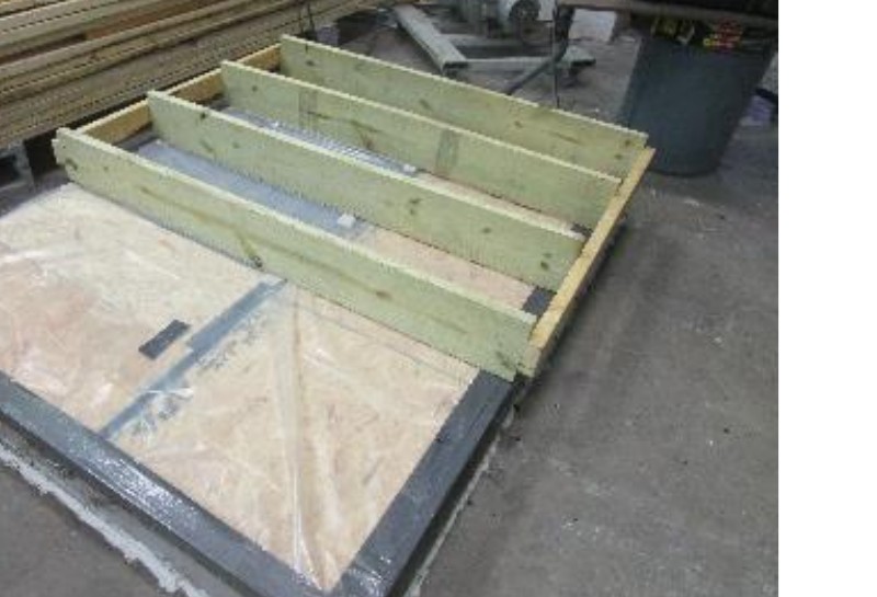 Typical test setup: inverted mock-up of grooved decking on Southern Yellow Pine joists with InvisiClip™ rail prepared for vacuum-chamber uplift testing.