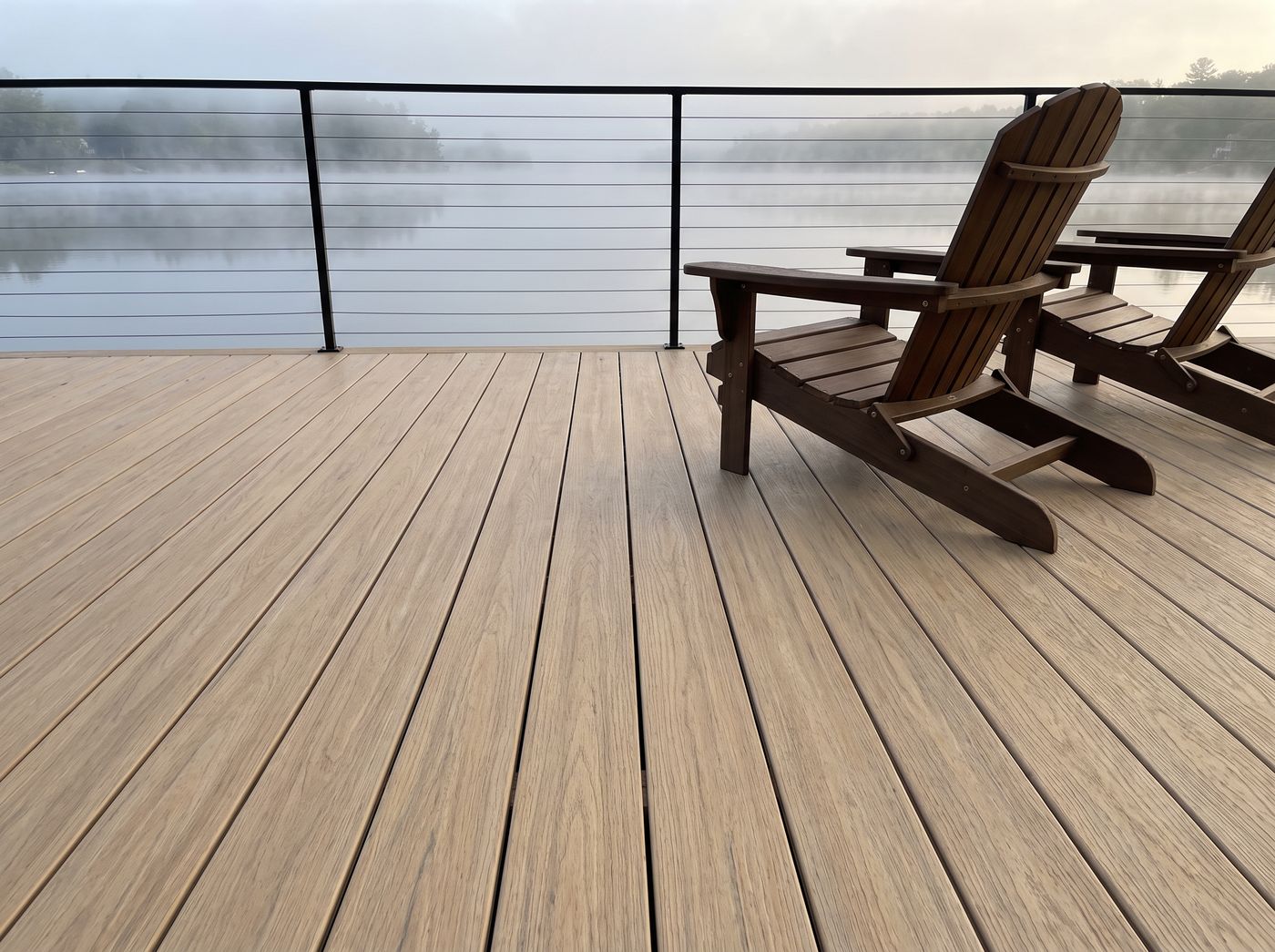 Aged Oak TrueGrain PVC decking on a lakeside deck with Adirondack chairs at sunrise