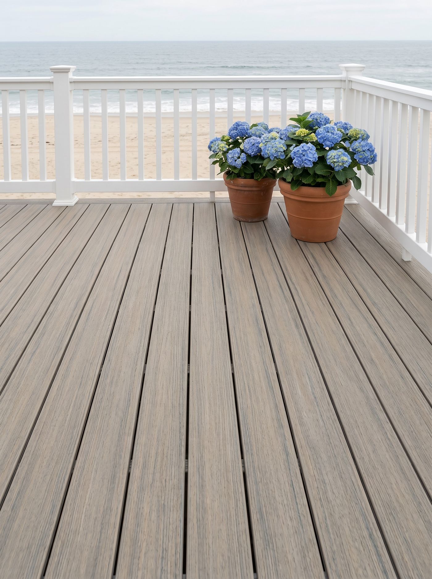 New England Birch TrueGrain PVC decking on a coastal cottage deck with white railing and hydrangeas